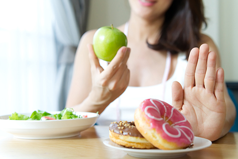 mujer con una manzana rechazando donuts